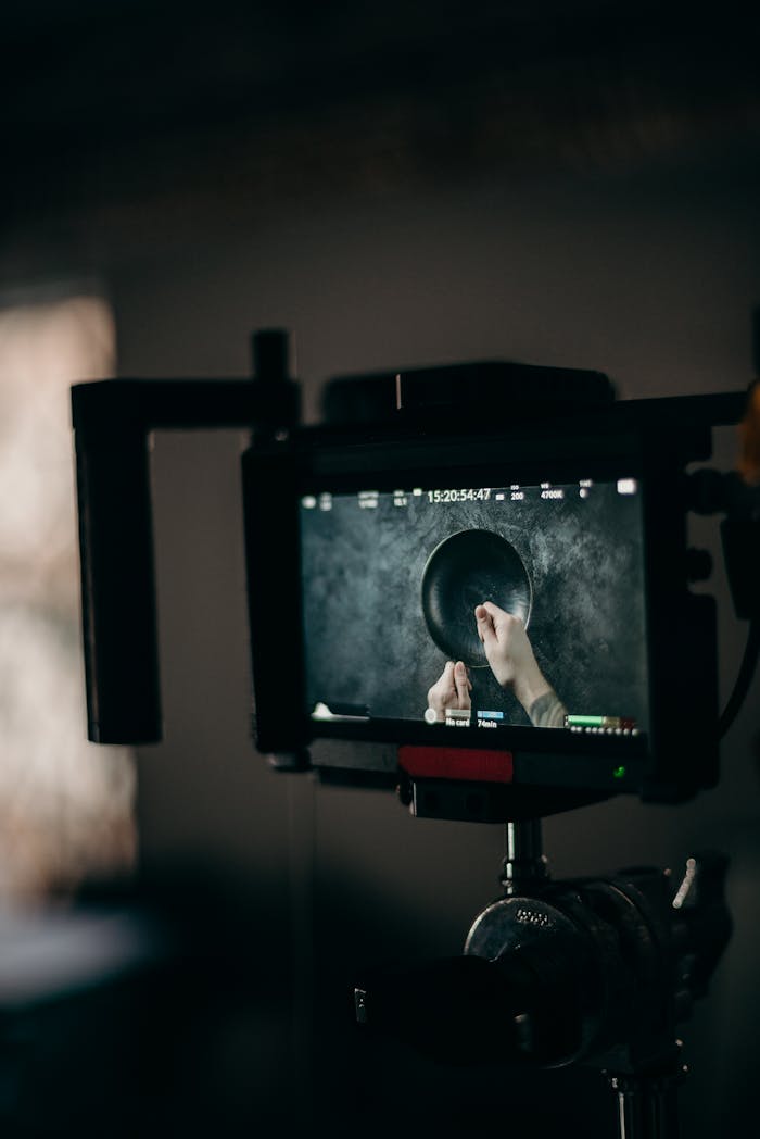 Close-up of a video production setup featuring a monitor displaying hands managing equipment.