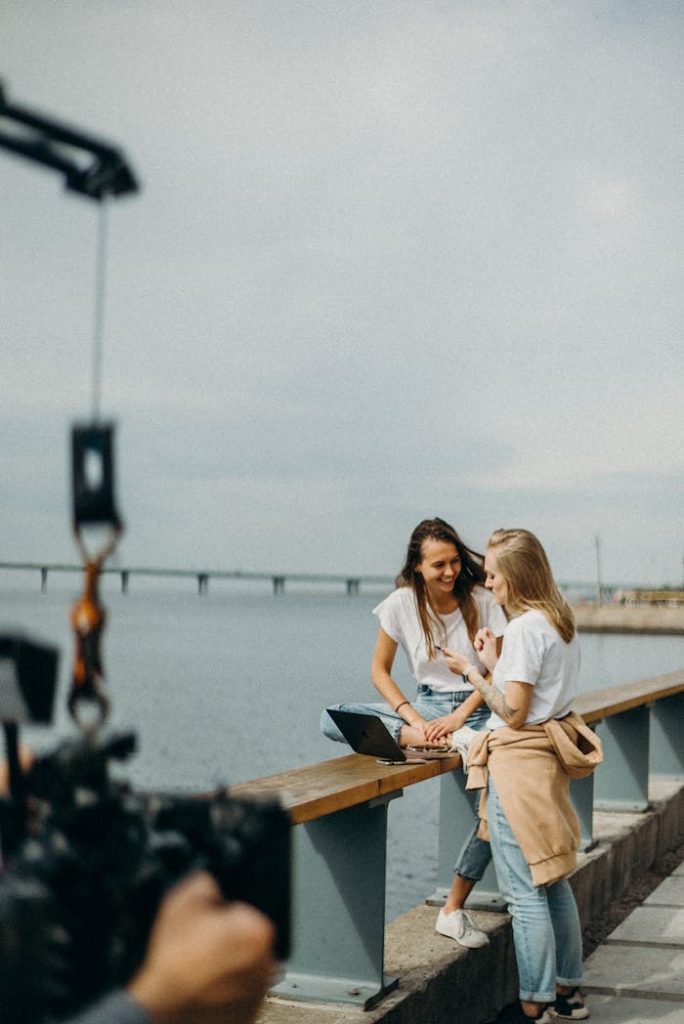 Two women enjoying a casual photo shoot by a scenic urban waterfront.